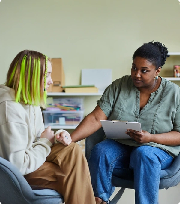 A counselor listens while holding a tablet during a one-on-one session