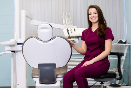 A dentist wearing a purple scrub suit