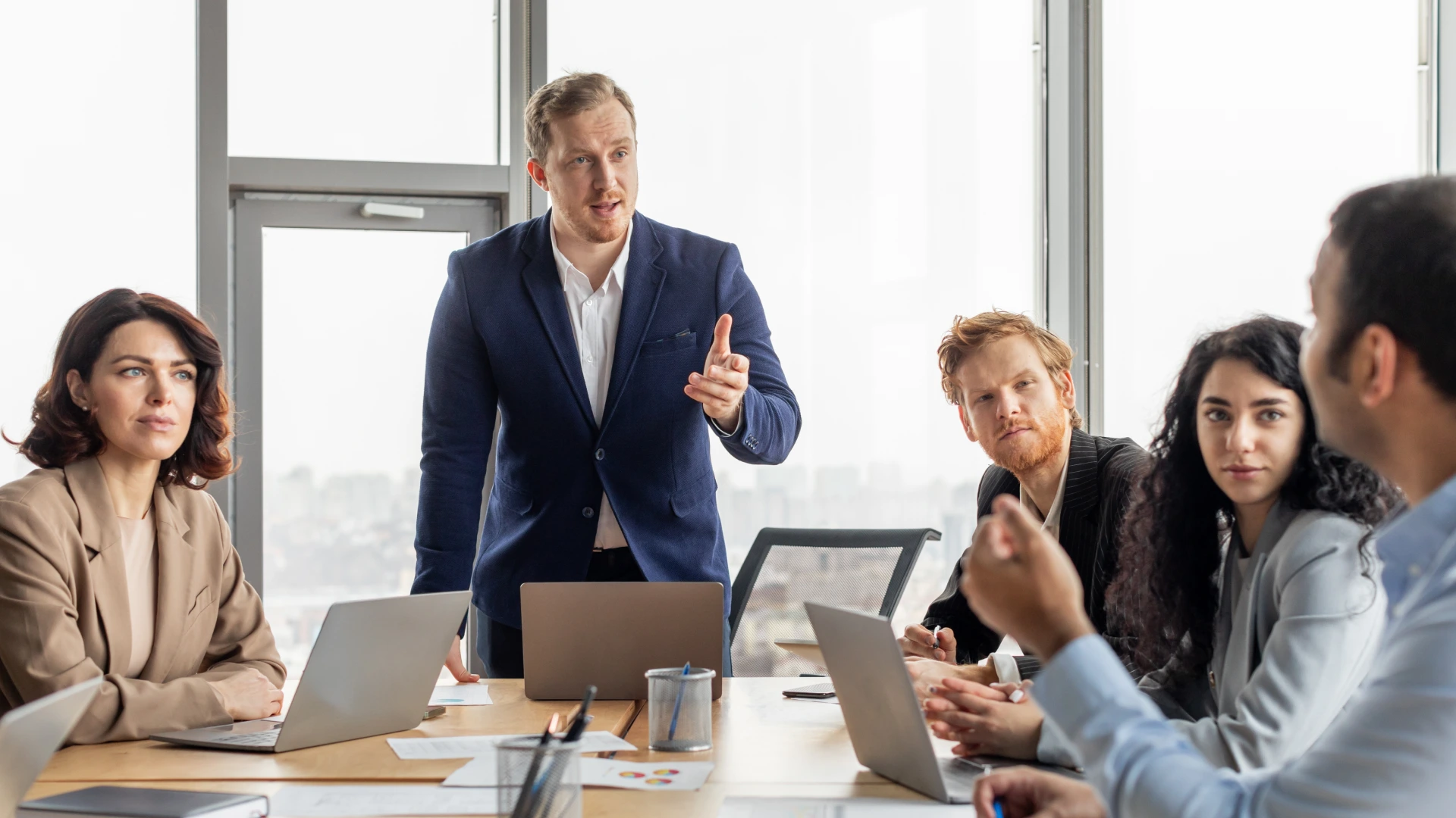 A group of business professionals are gathered around a conference table in a modern office