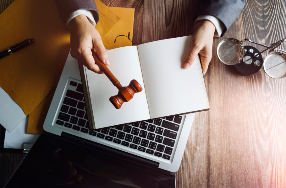 A person handle gavel above the laptop