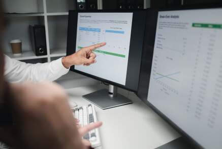 A person pointing the linegraph on a monitor