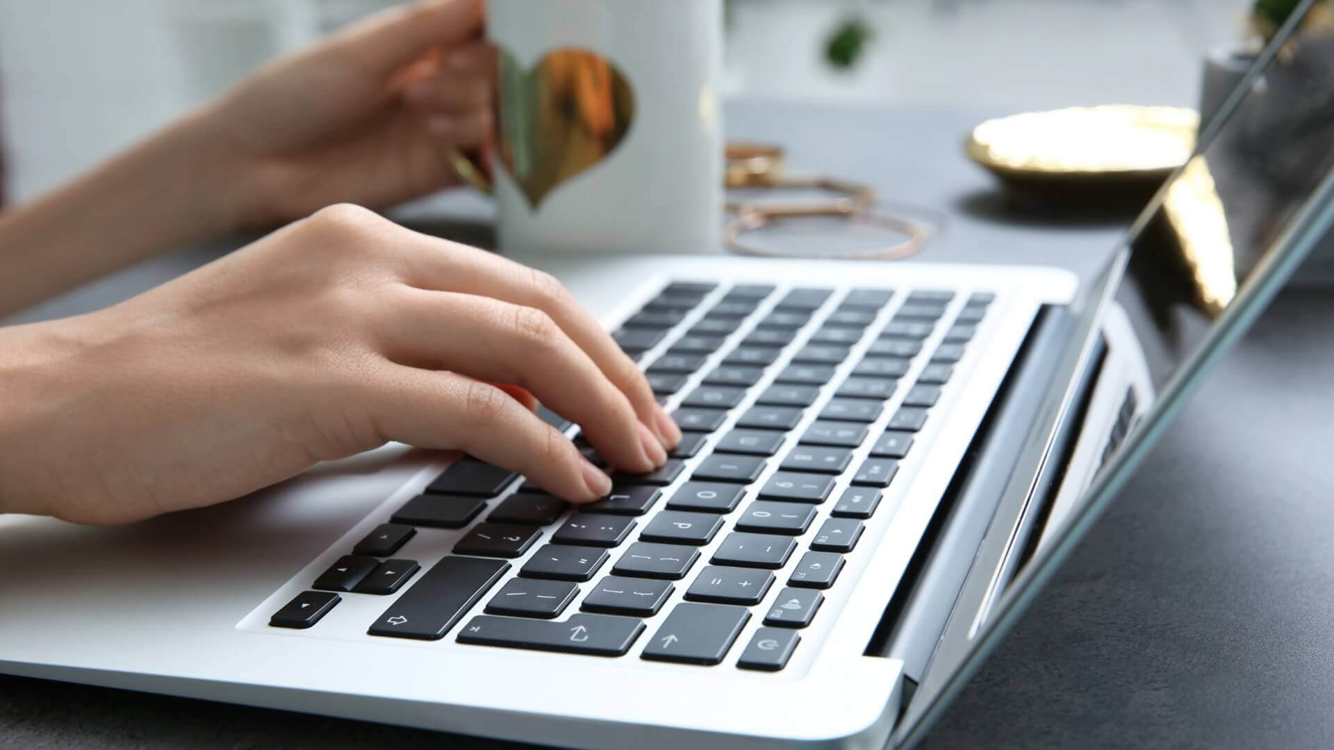 A person using laptop while drinking coffee