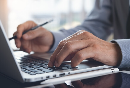 A person using typing in the keyboard while handling a pen