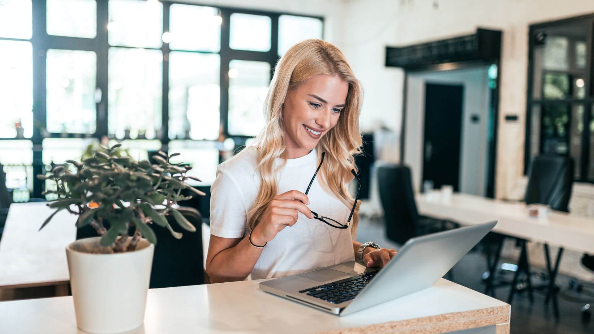 A smiling blonde woman using a laptop