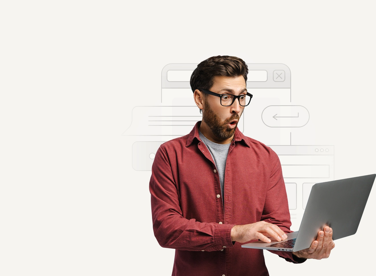 A surprised man in glasses and a red shirt looks at his laptop with an expressive reaction