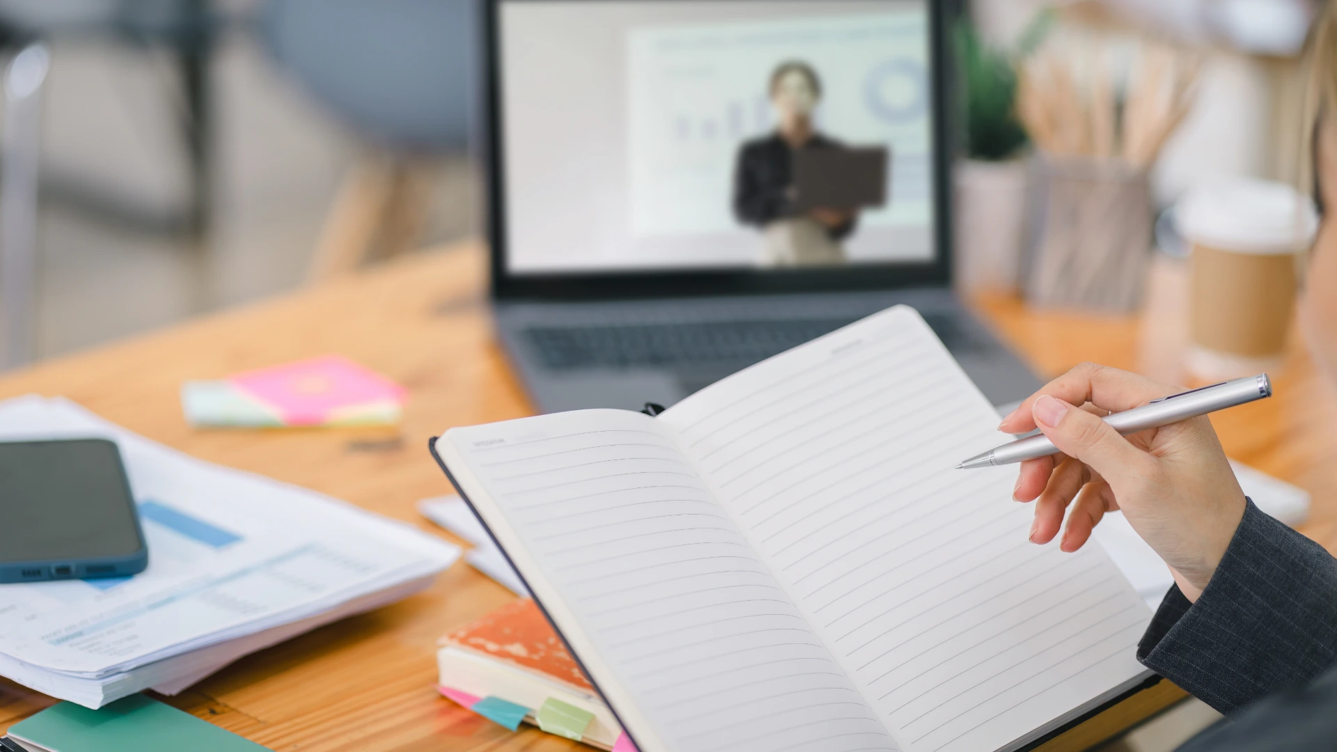 A woman taking notes while watching a tutorial