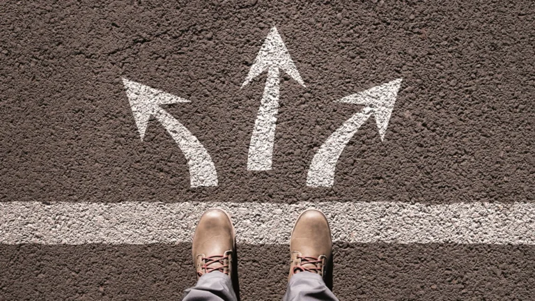 Arrows drawn on the asphalt in different directions in front of your feet in boots