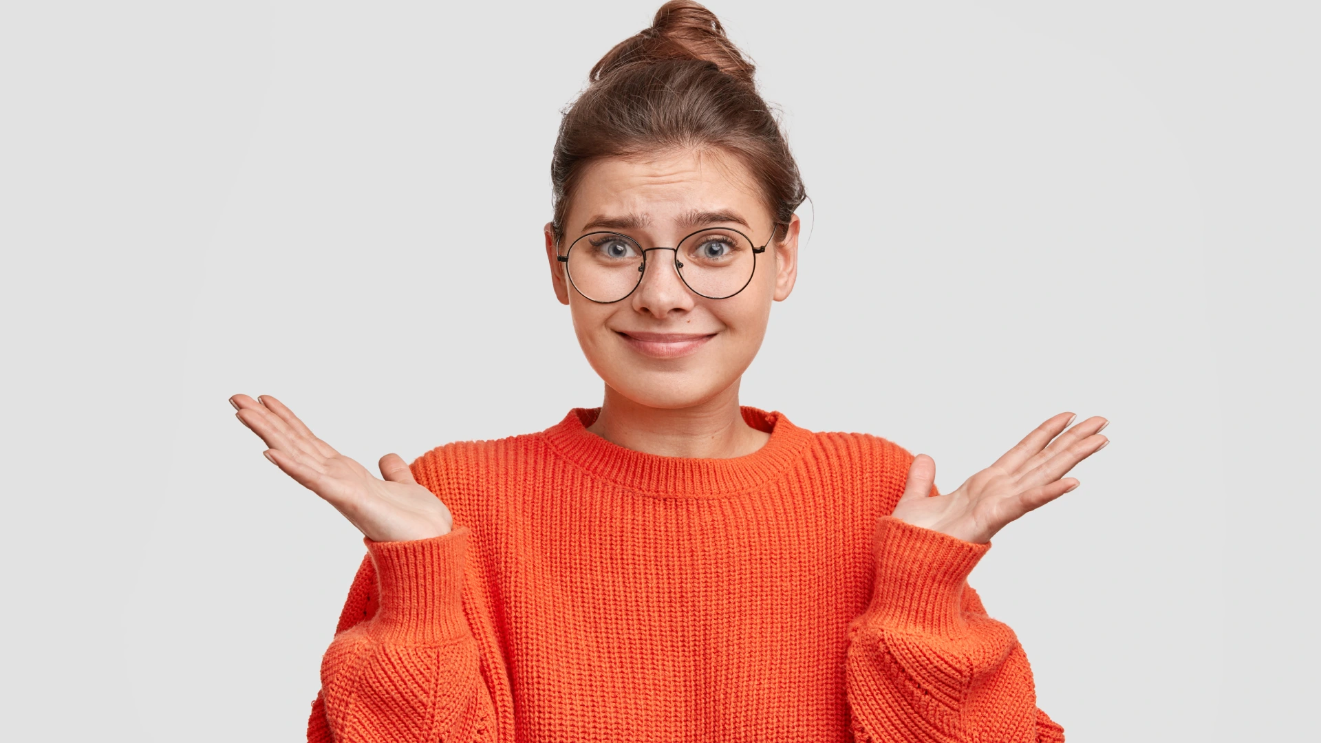 Beautiful young woman shrugs shoulders, wearing red sweater