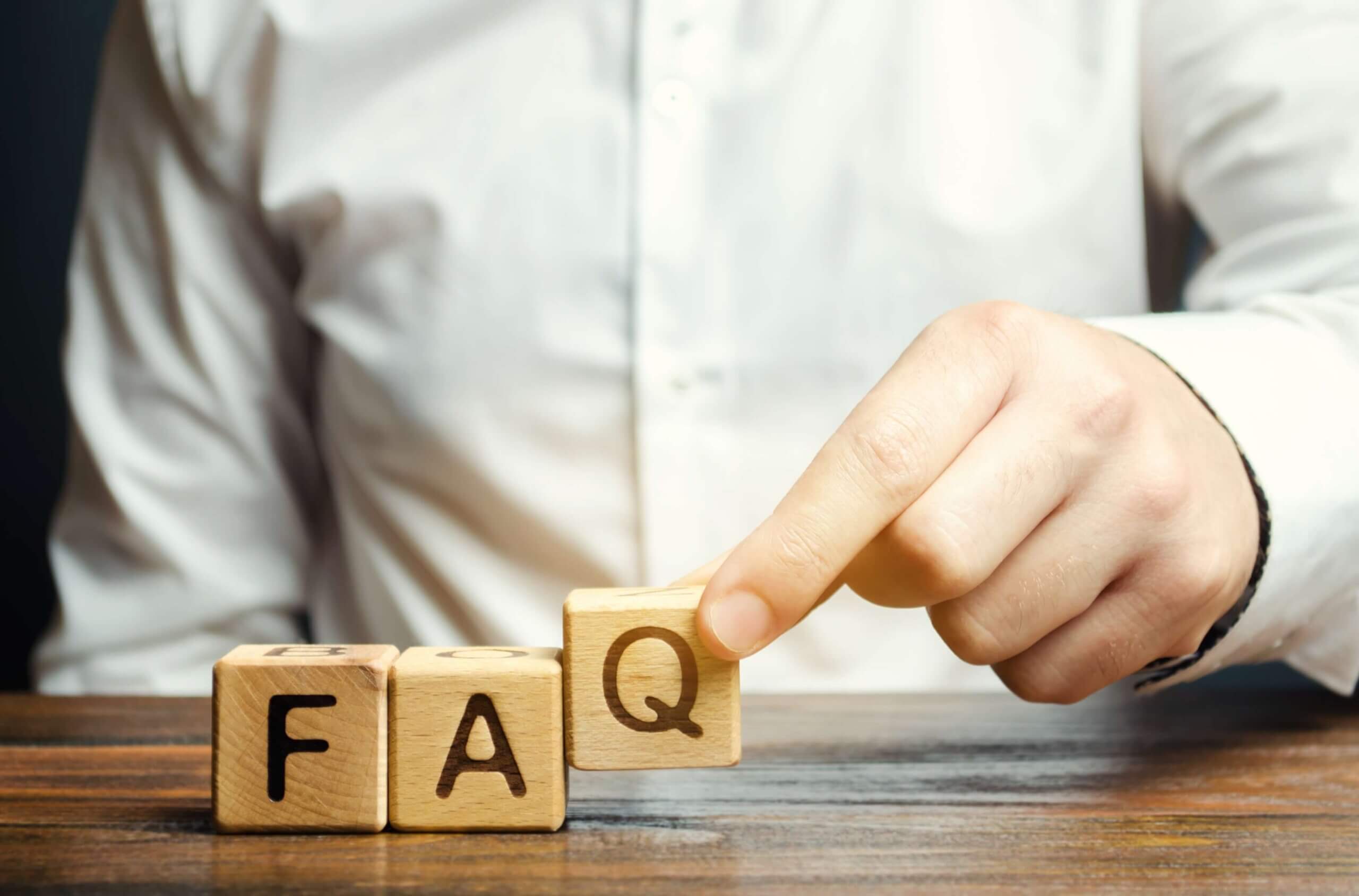 Businessman puts wooden blocks with the word faq