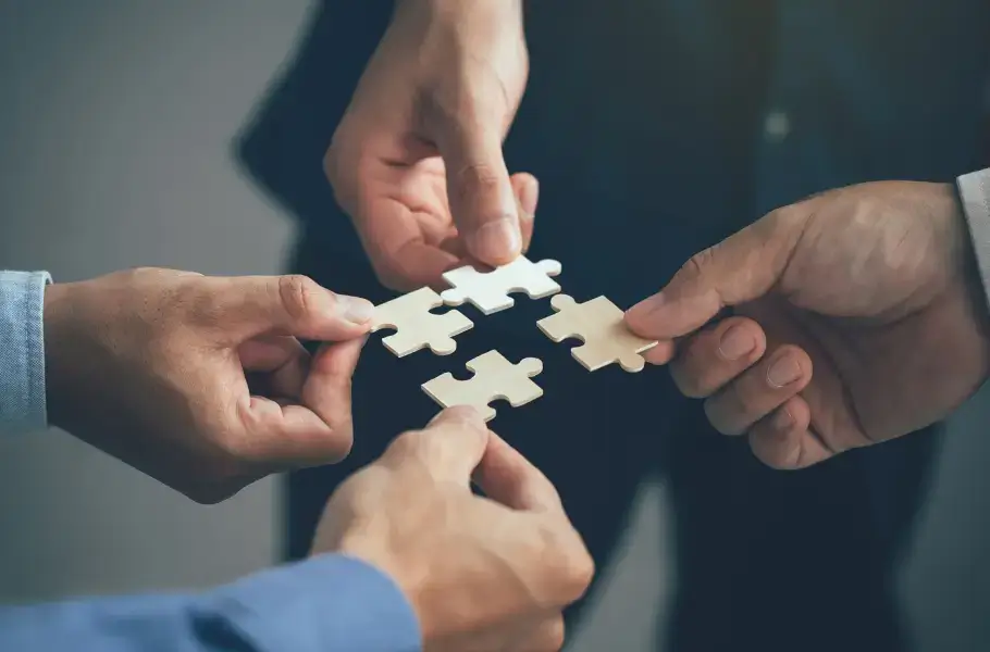 Hands holding puzzle pieces in a collaborative effort