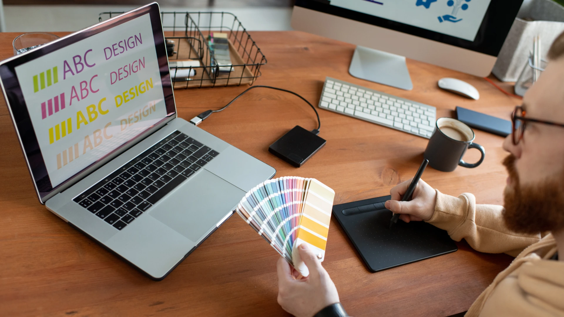 Concentrated male designer writing text on drawing pad and choosing color of font