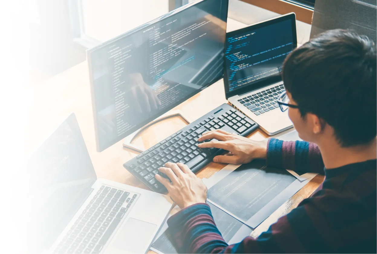 Developer working with code on multiple screens