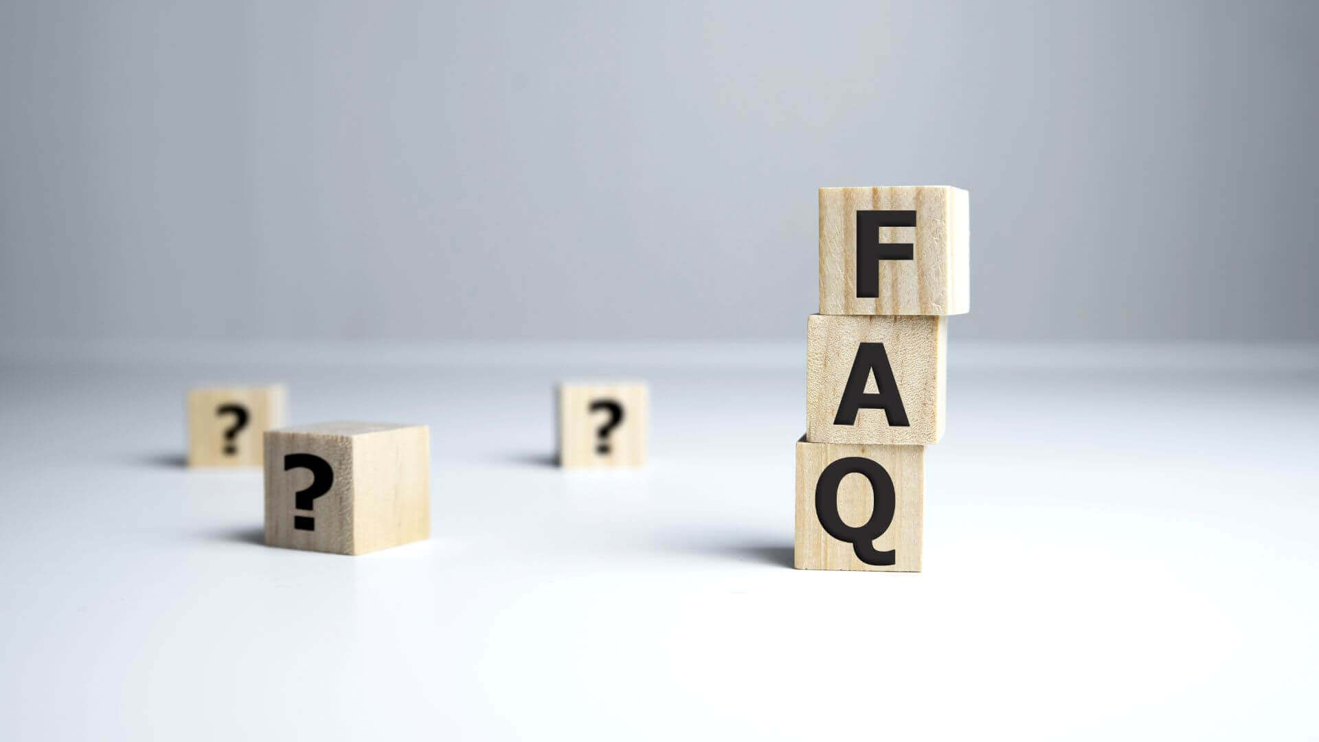 FAQ word in a block of wood with grey background