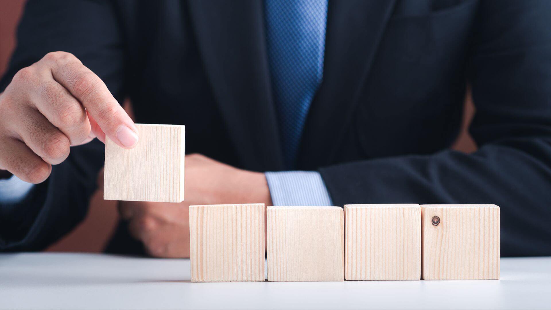 Hand of businessman arranging empty wooden blocks