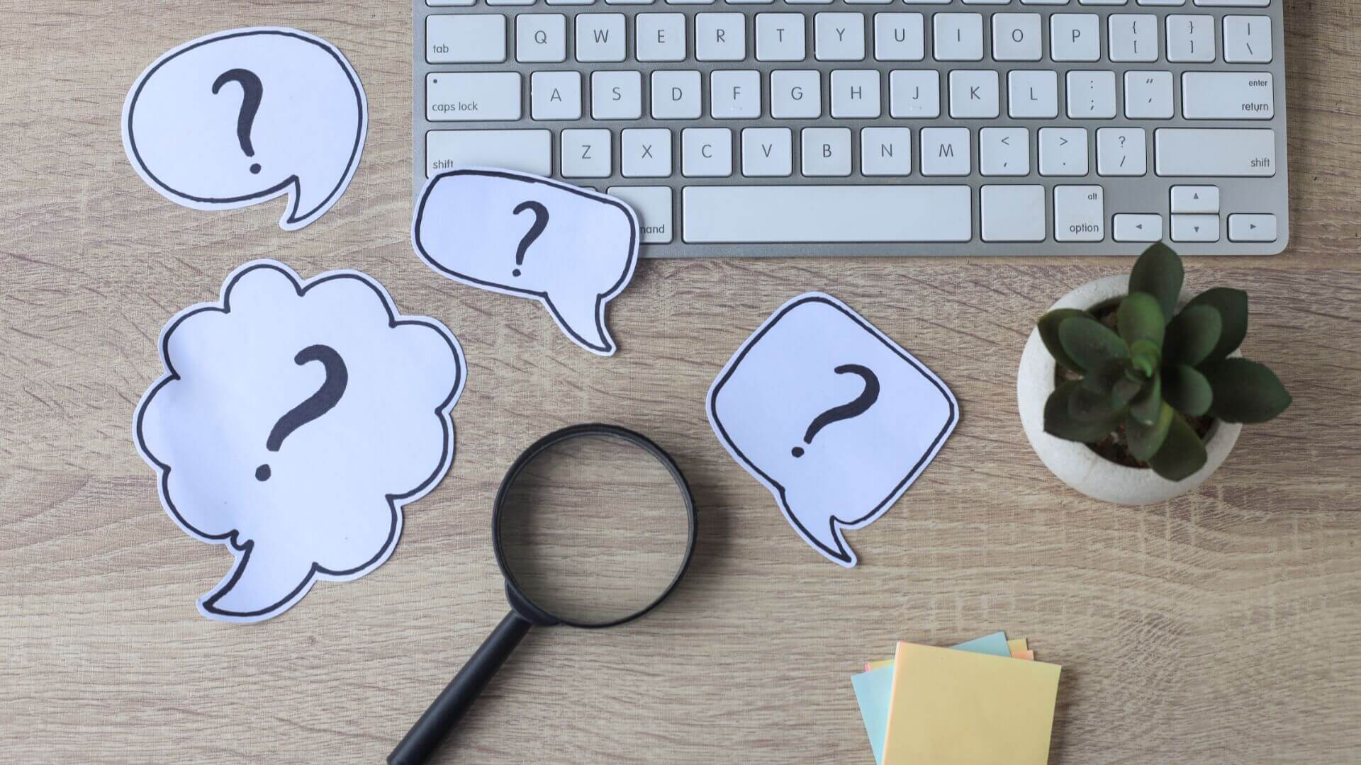 Magnifiying glass above the table with question mark notes