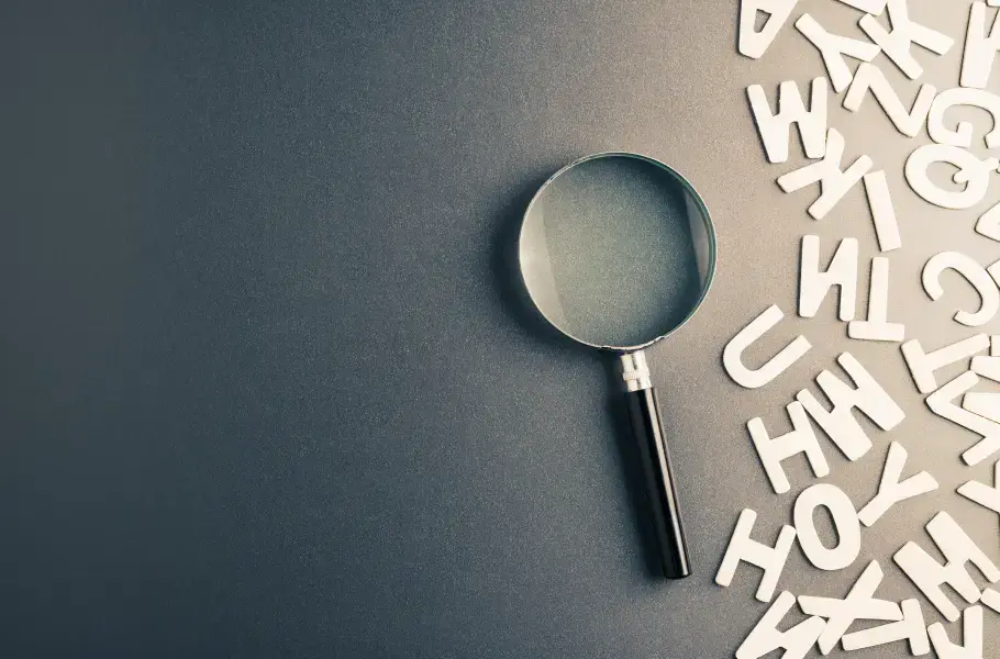 Magnifying glass with scattered letters on a dark background