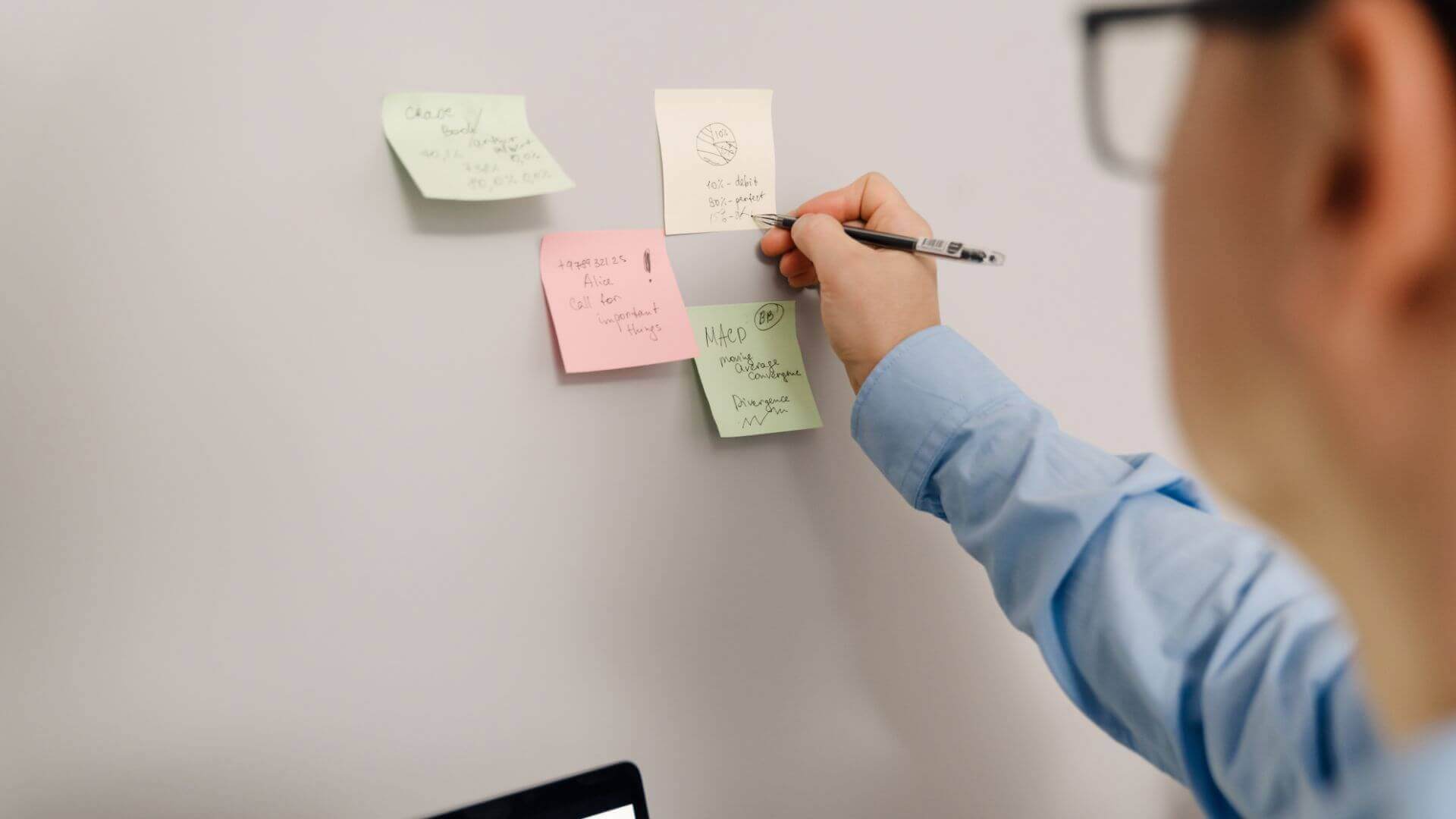 Man in Glasses Taking Notes on Stickers on the Wall