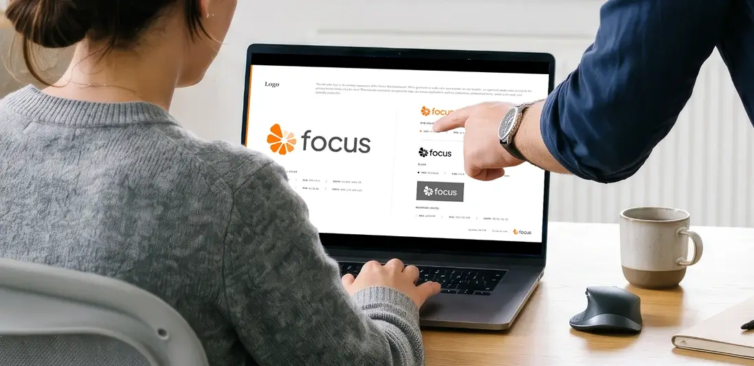Person reviewing logo concepts of focus solution company on a laptop with a colleague