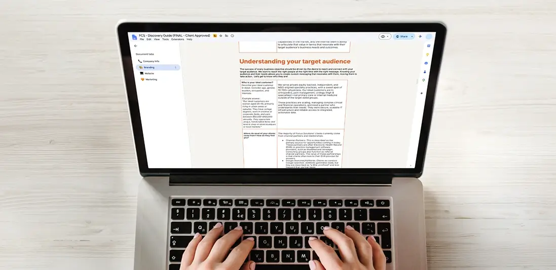 Person typing on a laptop displaying a target audience document