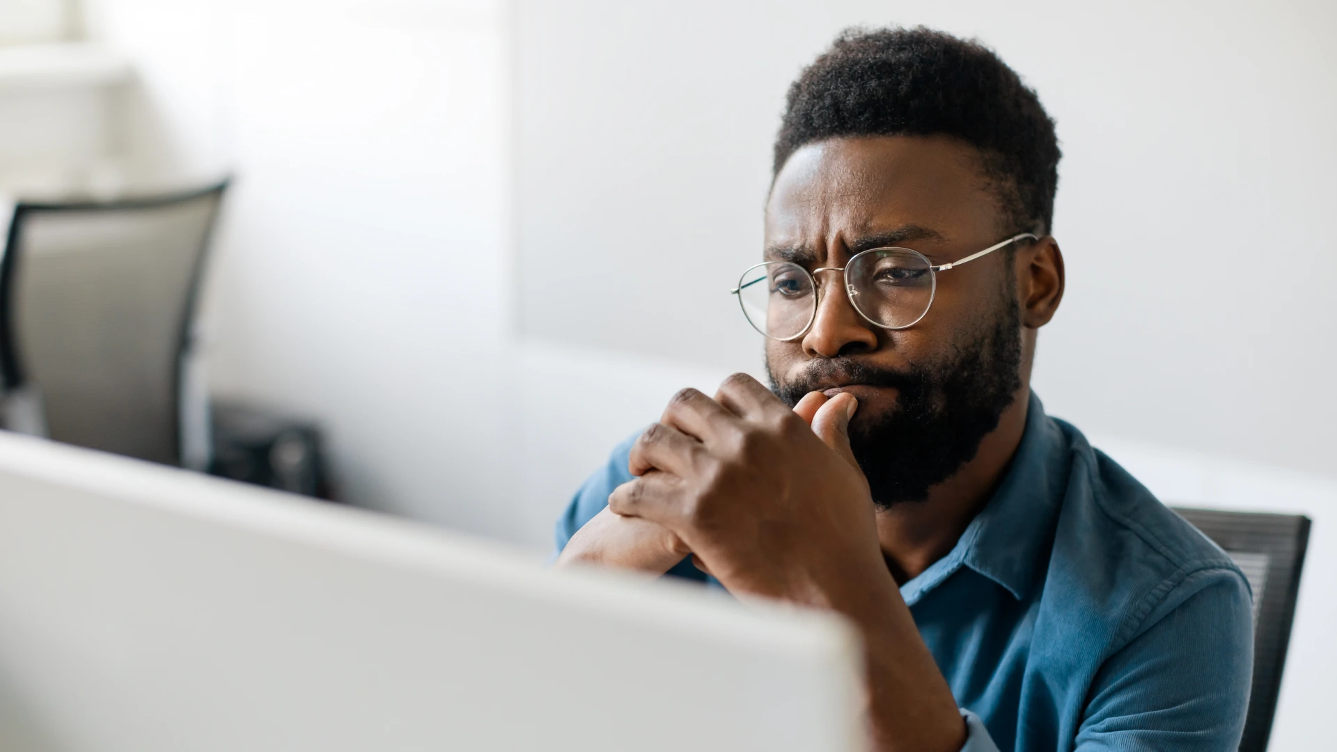 Thoughtful black man in eyeglasses stack with hard task, looking at computer screen