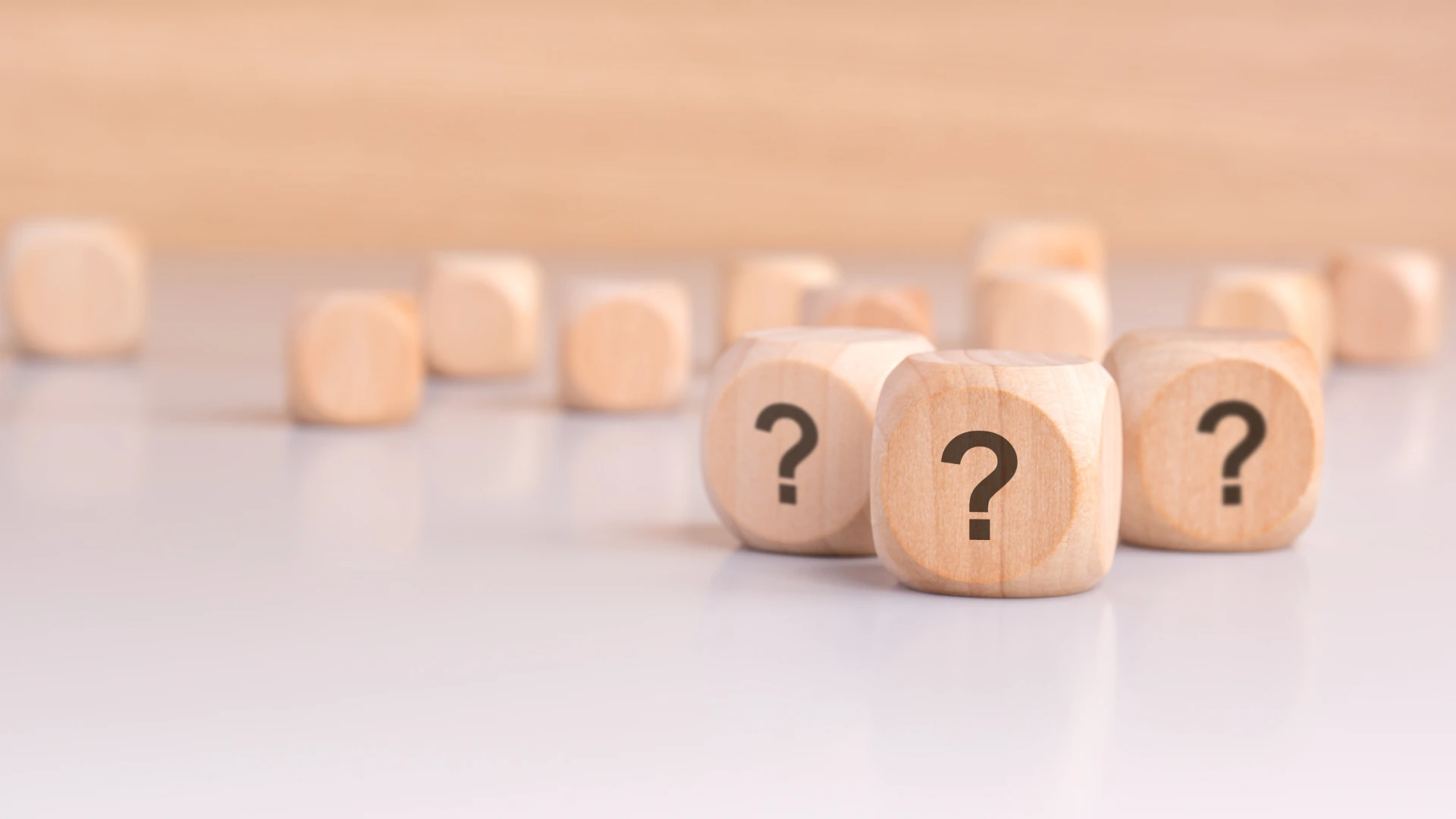 Three wooden cubes with question marks over a light gray background