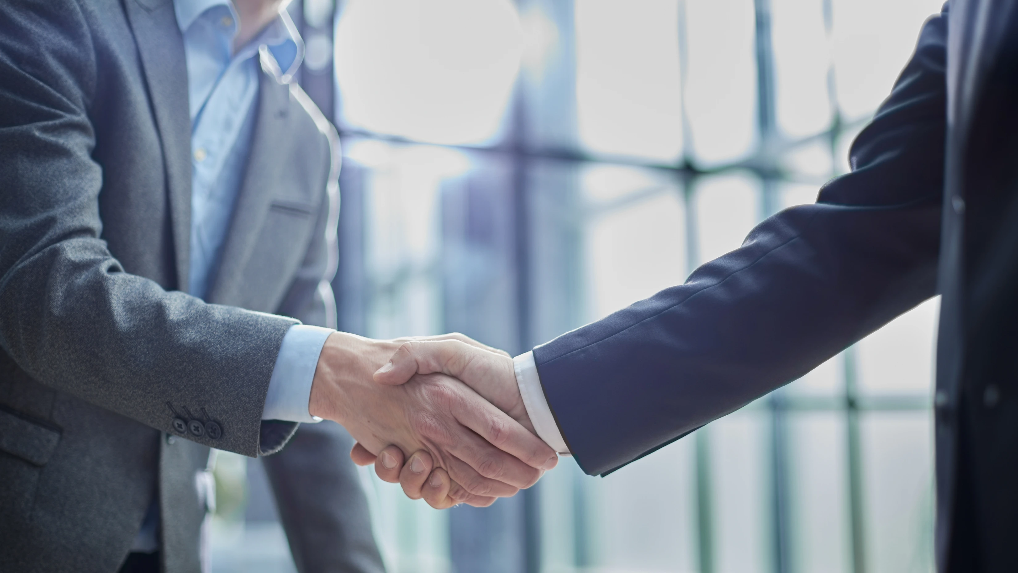 Two diverse professional business men executive leaders shaking hands at office meeting