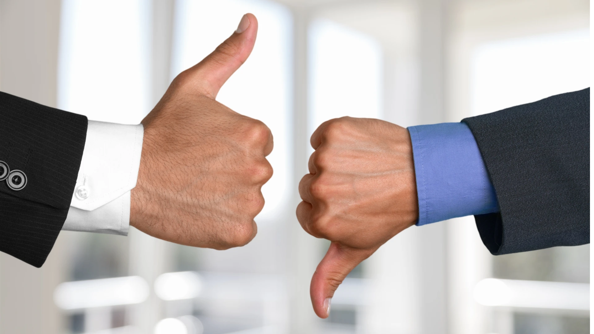 Two hands showing different gestures. Thumb up and thumb down