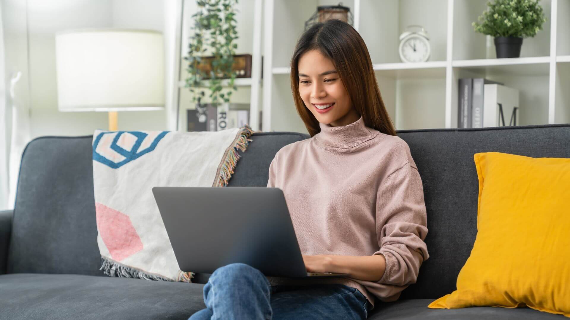 Woman using laptop while sitting in sofa