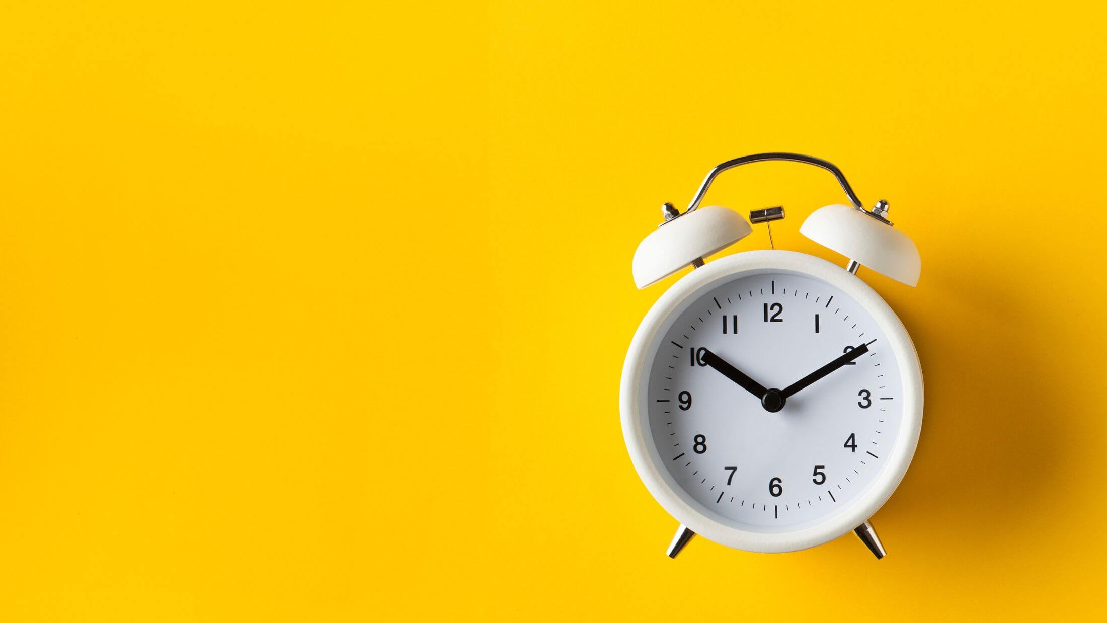 alarm clock placed in right side of a yellow background