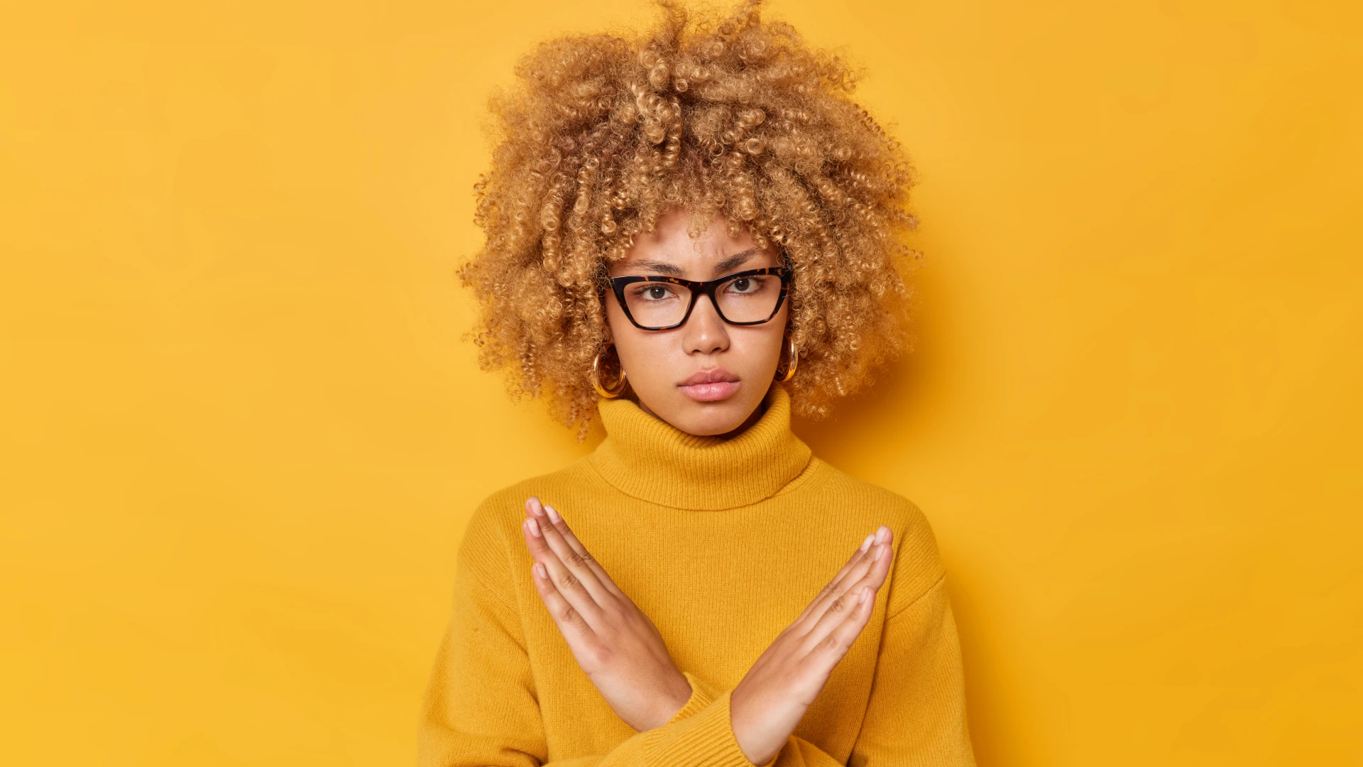 A blonde curly haired woman shows cross makes stop