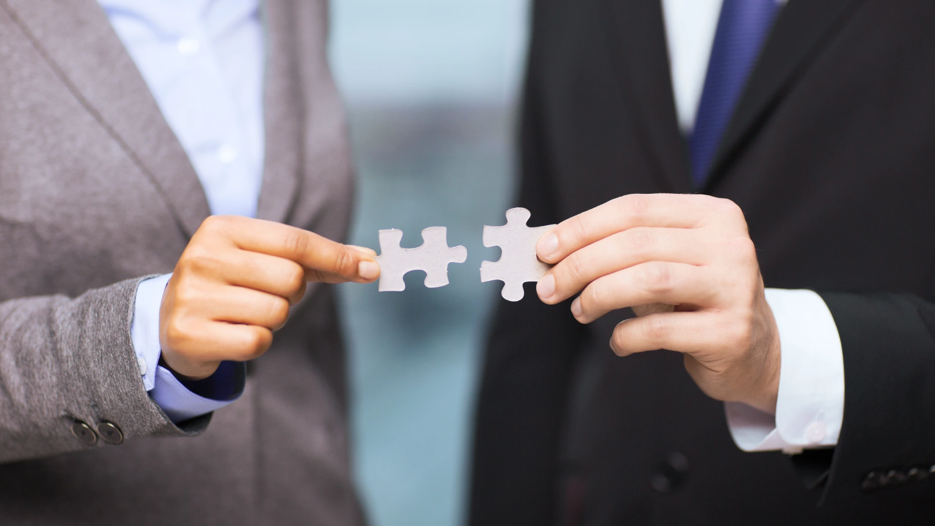businessman and businesswoman trying to connect puzzle pieces in office