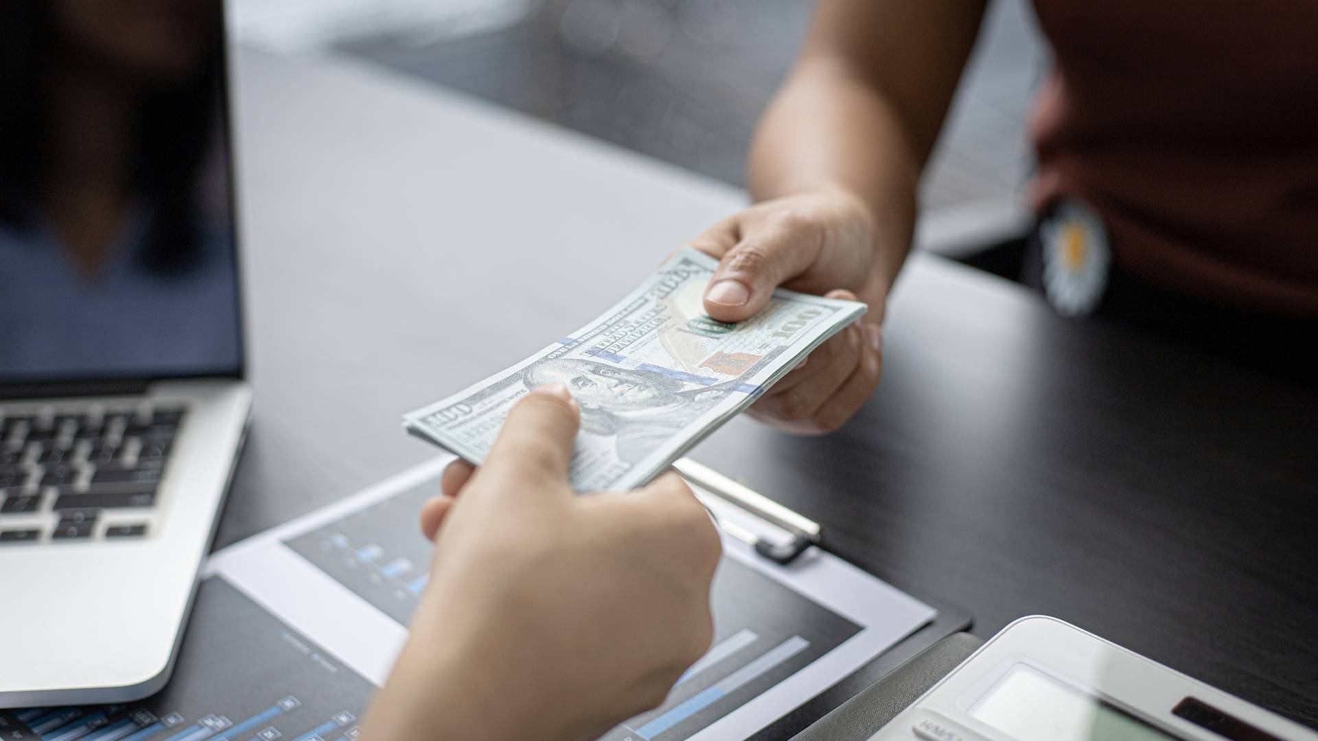 businessmen handing over dollar bills