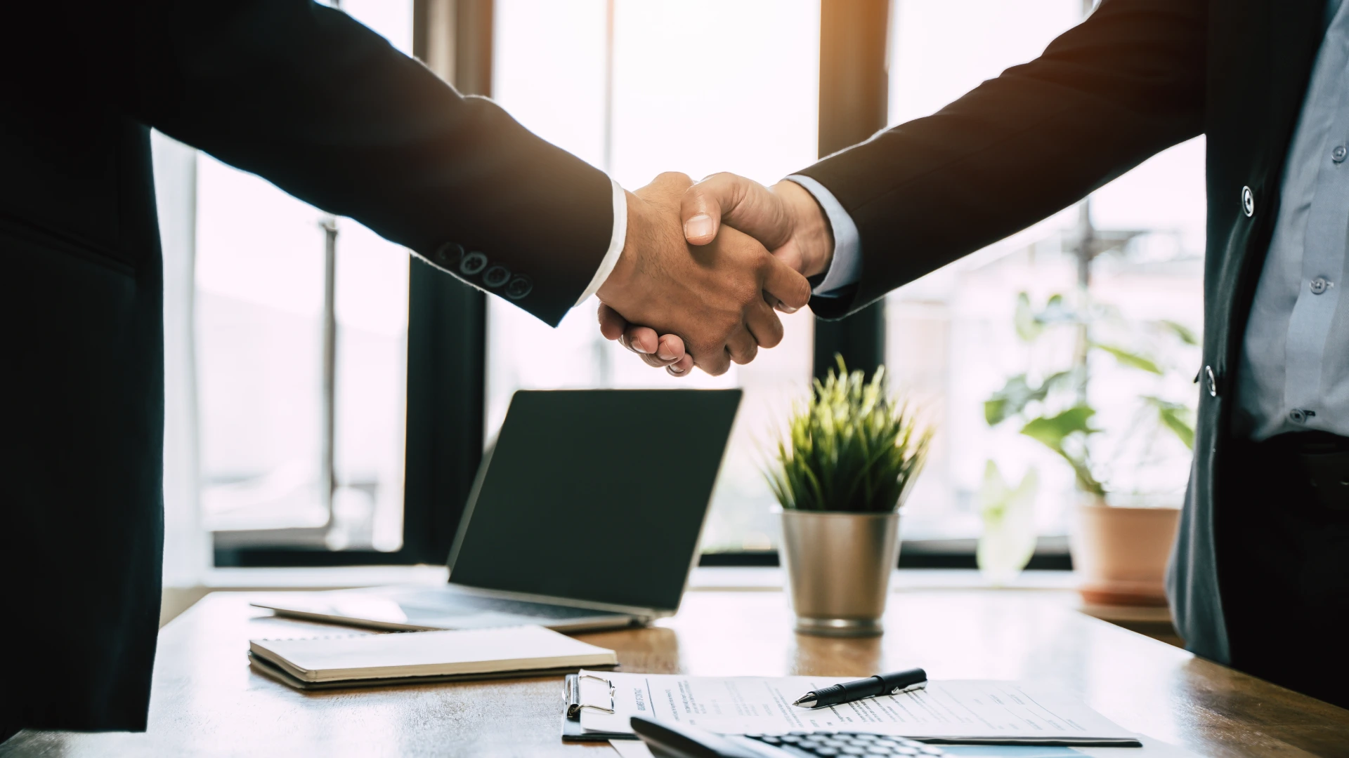 close-up view hands of agent and client shaking hands after signed contract