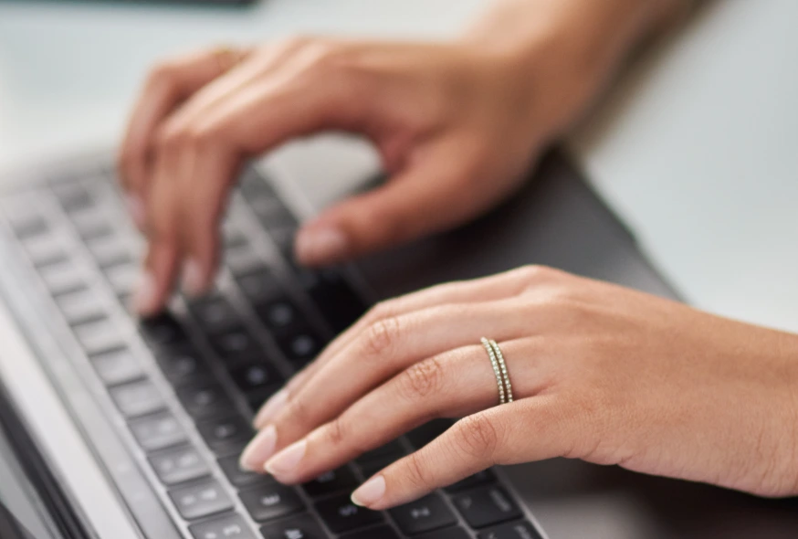 closeup image of a woman typing on her laptop