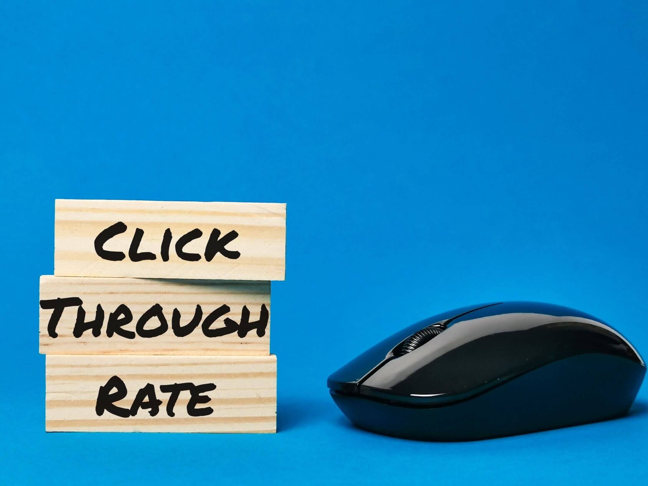 Three wooden blocks with letters spelling out 'CTR' for 'Click Through Rate', next to a computer mouse, representing the concept of digital marketing metrics.