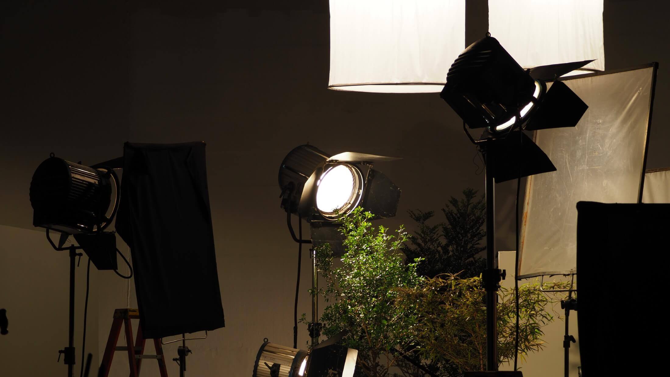 Professional video production lights in a dark studio setting, illuminating a scene with a camera set up for filming.