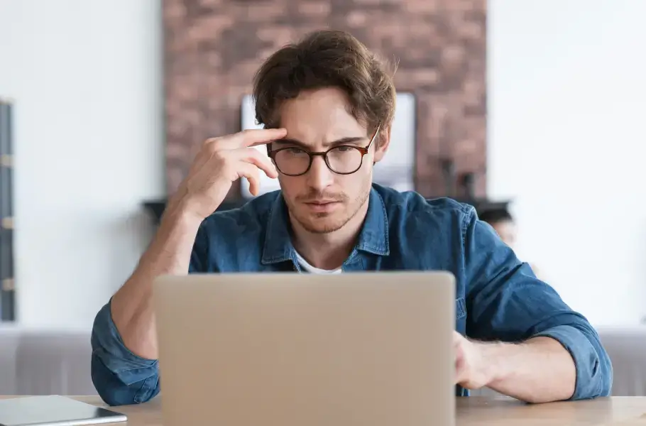 Man looking focused while working on a laptop