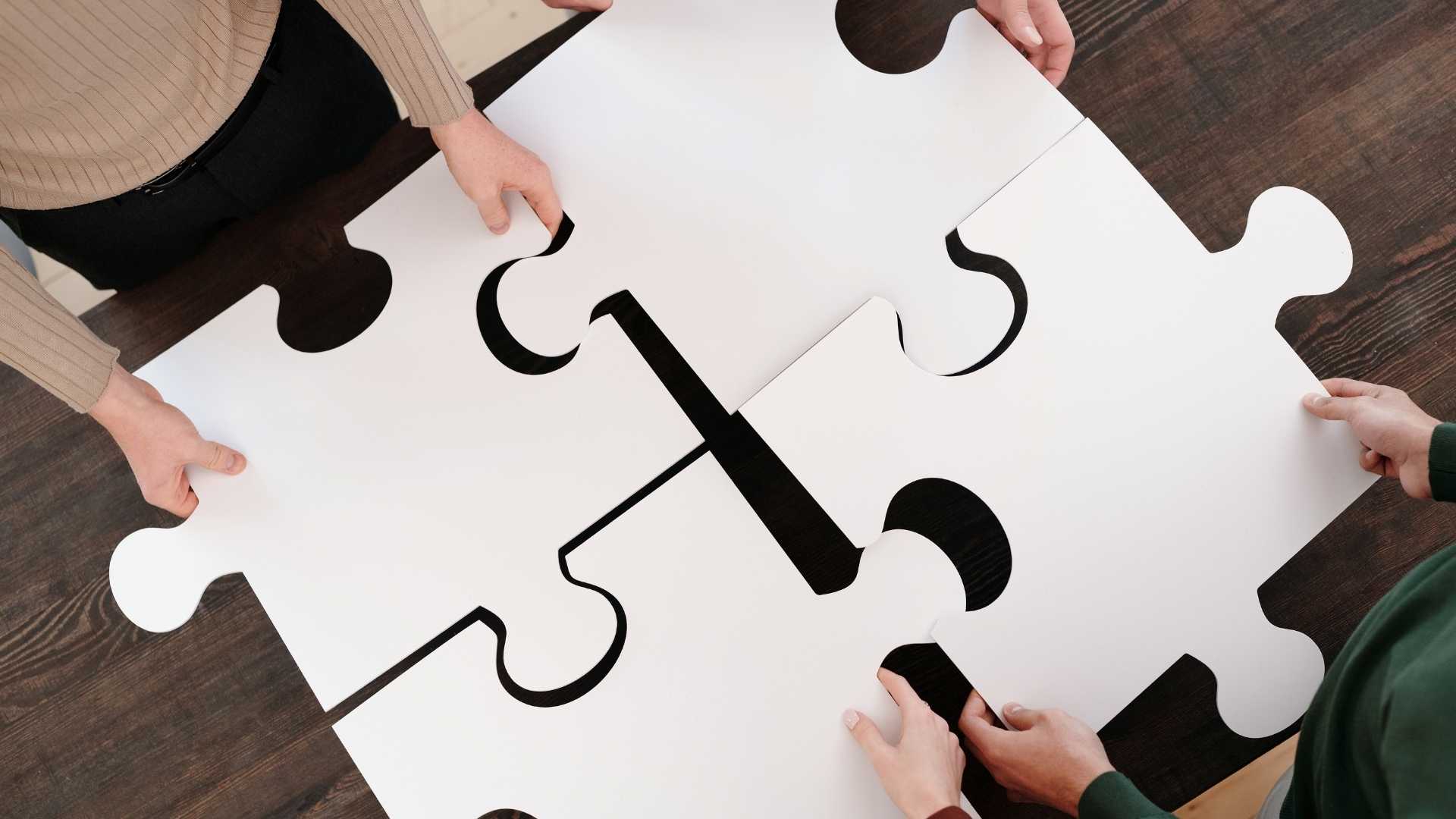 four people forming a big jigsaw puzzle to complete