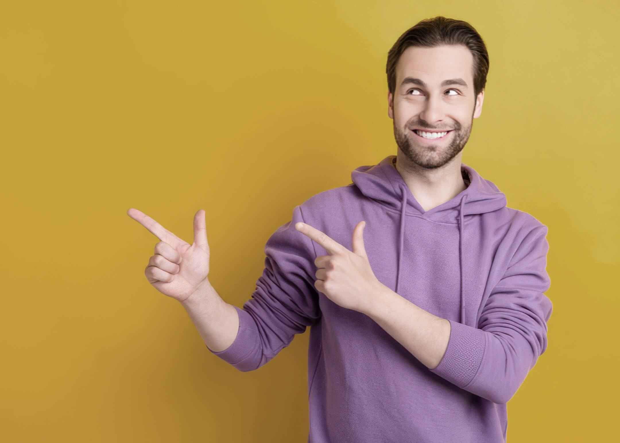 guy point forefinger empty space recommend wear purple hoodie isolated yellow color background