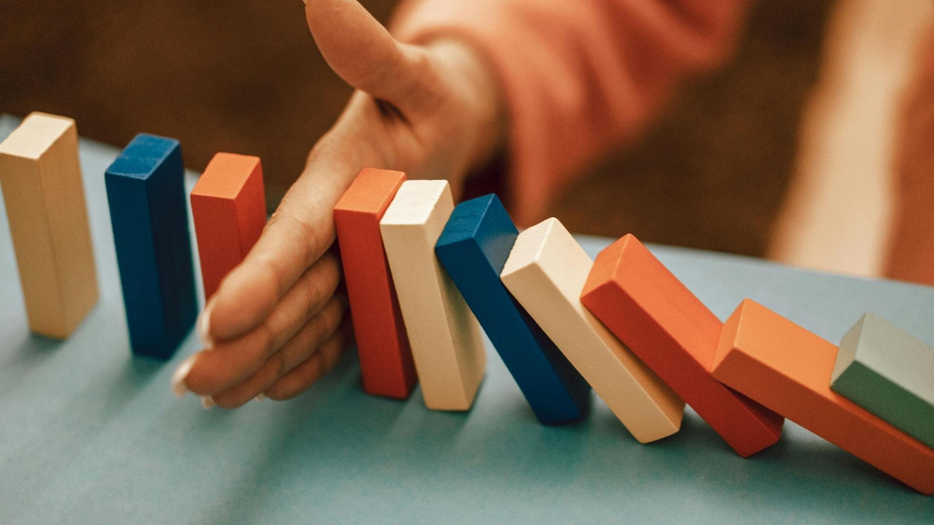 hand stopping dominos from falling down