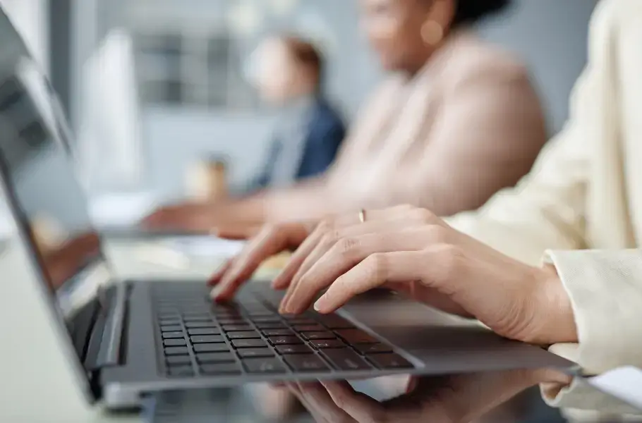 Close-up of hands typing on a laptop keyboard with blurred background