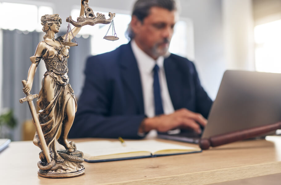 lawyer using his laptop and a justice lady bust