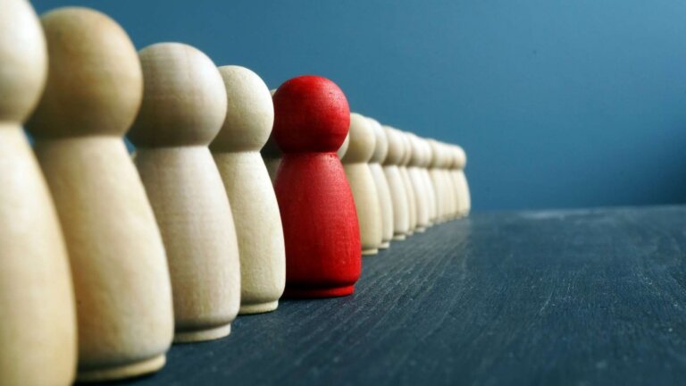 line of wooden figures with the red one upfront