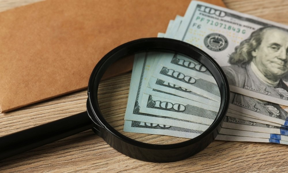magnifying glass on top of dollar bills