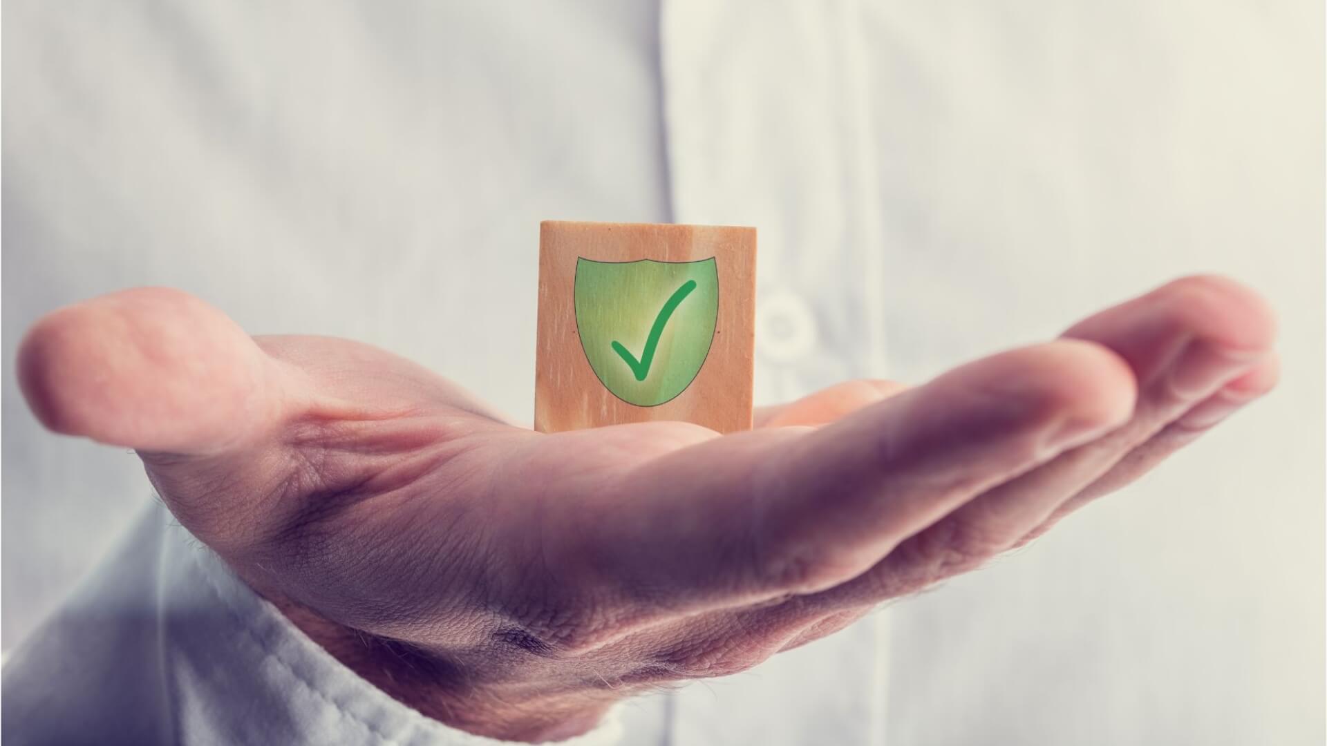 Man holding a square box with shield and check icon