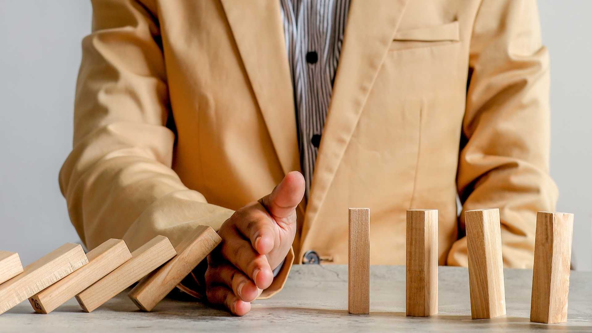 man in the suit preventing the other wood blocks from falling
