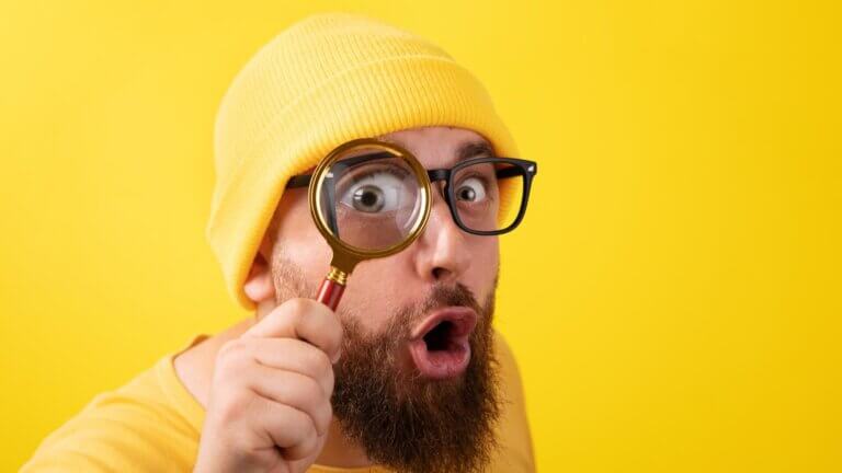 man in yellow shirt looking at magnifying glass