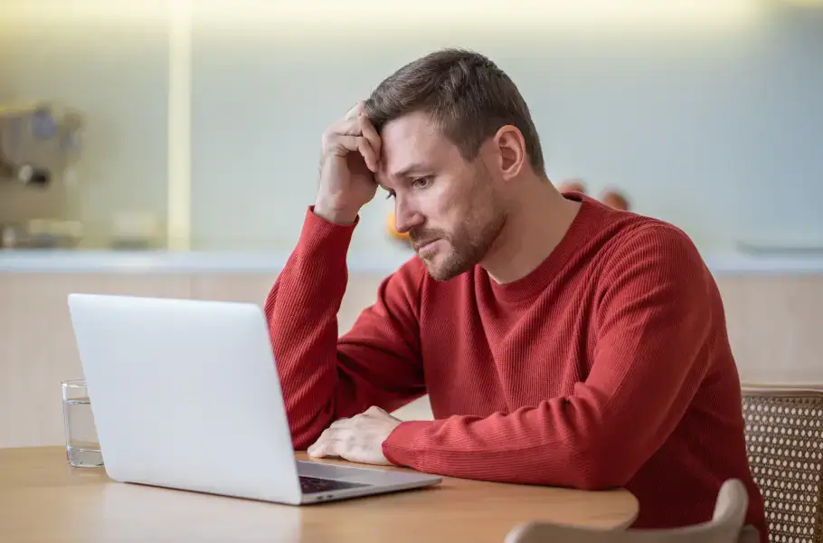 Man looking stressed while working on a laptop