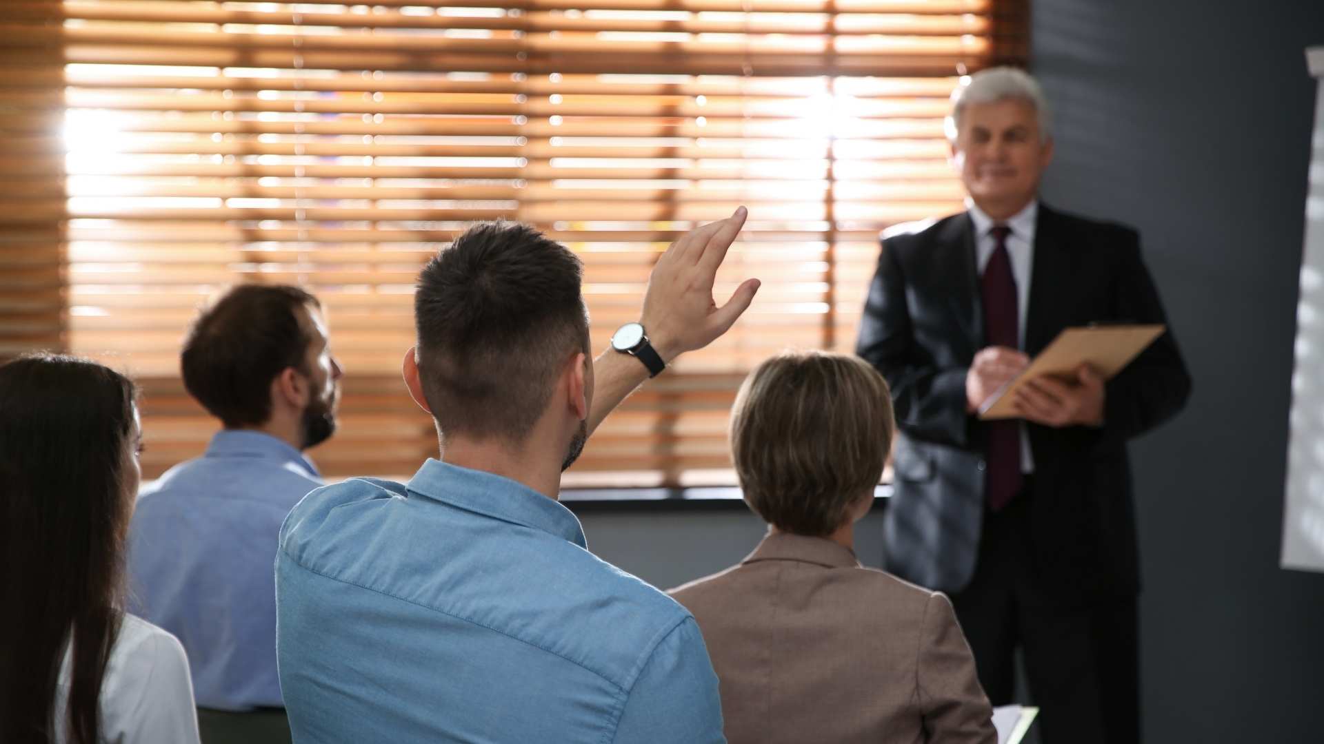 man raising his hand during meeting