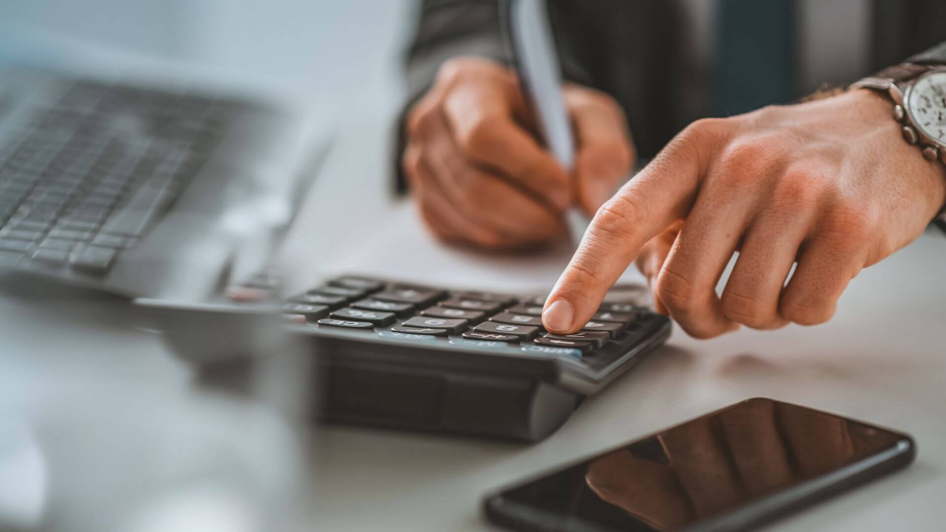 man using his calculator and a phone